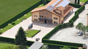 A two-story building with solar panels on the roof, a parking lot, and well-maintained hedges.