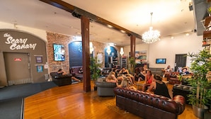 A spacious lounge area with leather sofas and a brick wall. - Nomads Sydney - Hostel (Sydney)