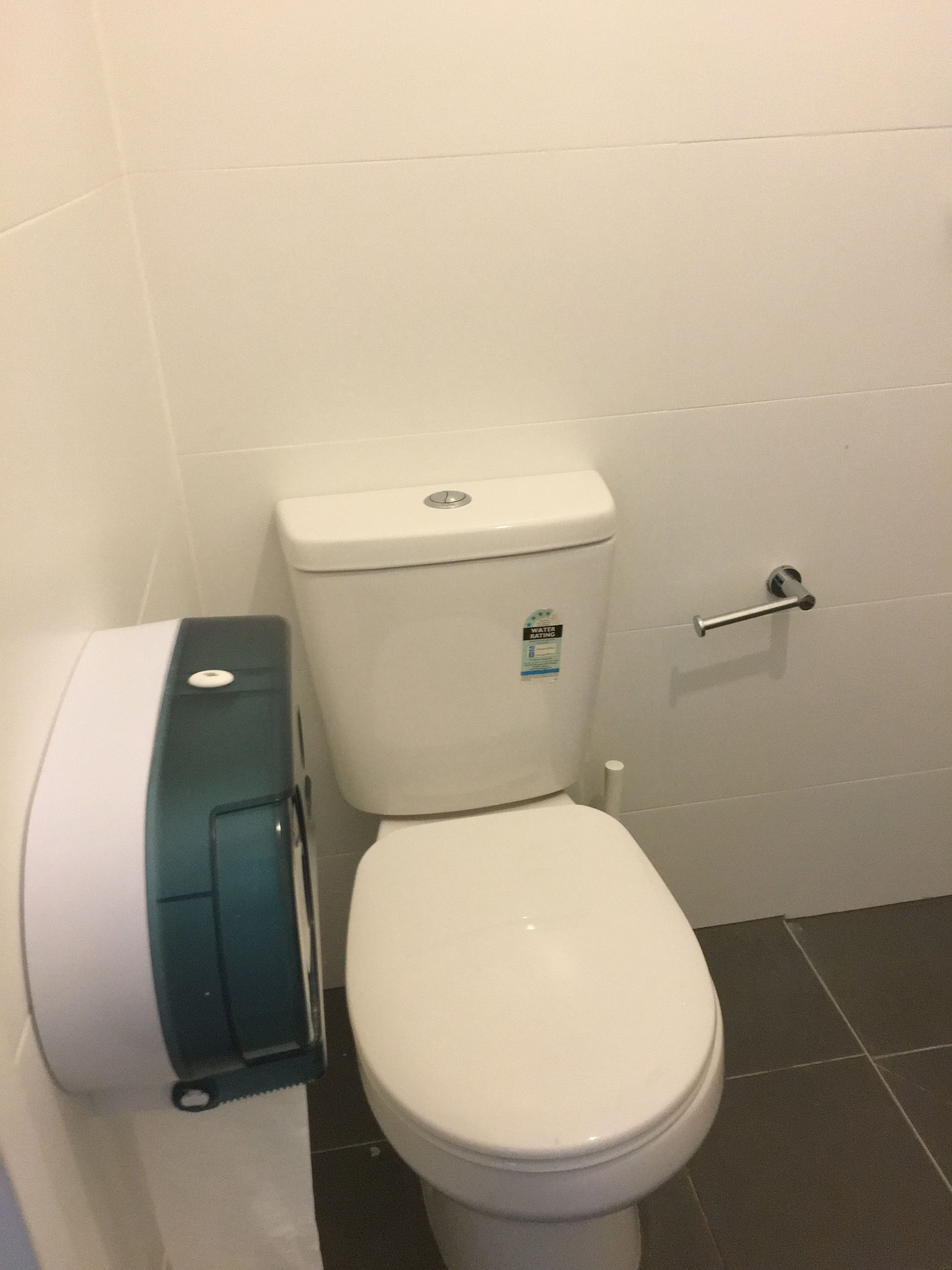 A toilet with a water-saving sticker, a toilet paper holder, and a door handle.