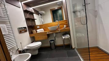 A modern bathroom with a wooden vanity, a glass shower enclosure, a bidet, and a toilet.