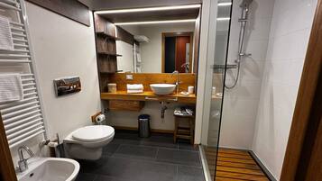 Un bagno compatto con bidet, toilette e cabina doccia.