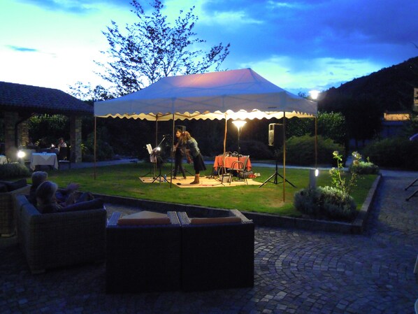 An outdoor patio area with a covered seating area, a table with chairs, and a speaker setup. - Hotel Cortese (Armeno)