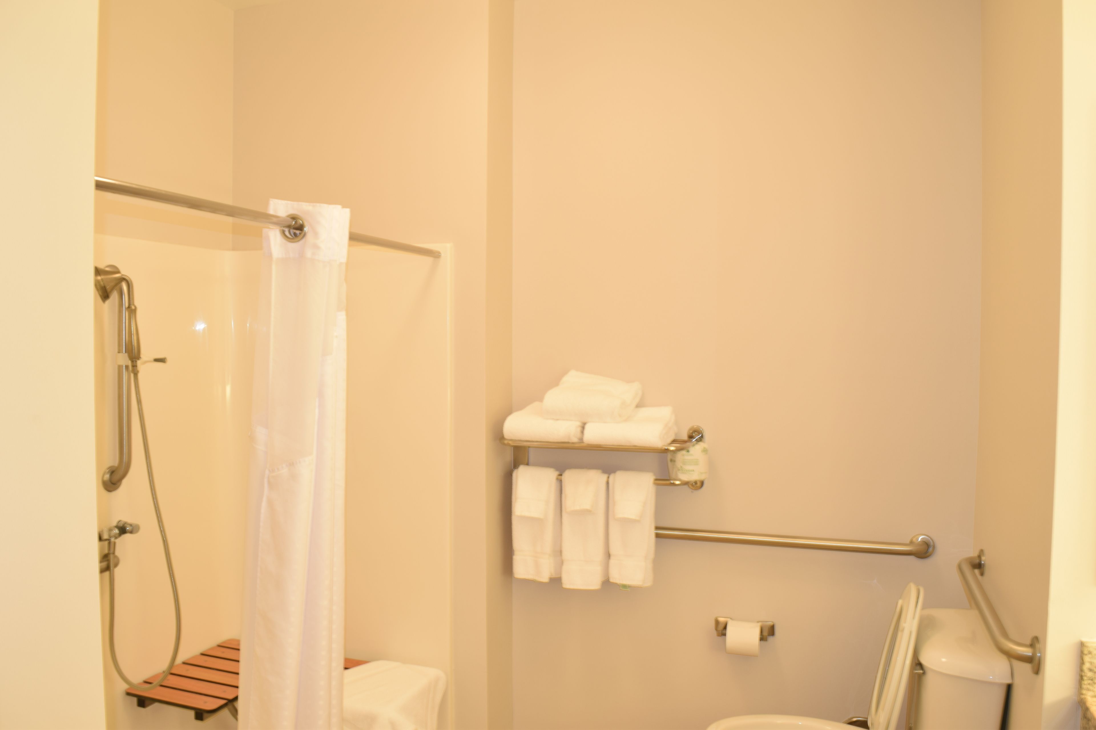 Baño con ducha, inodoro y toallero con toallas.