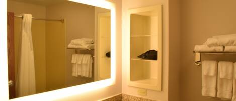 A bathroom with a large mirror, a sink with a faucet, a towel rack, and a shelf with towels.
