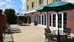 A patio area with outdoor seating, including chairs and tables, and a covered area with umbrellas.