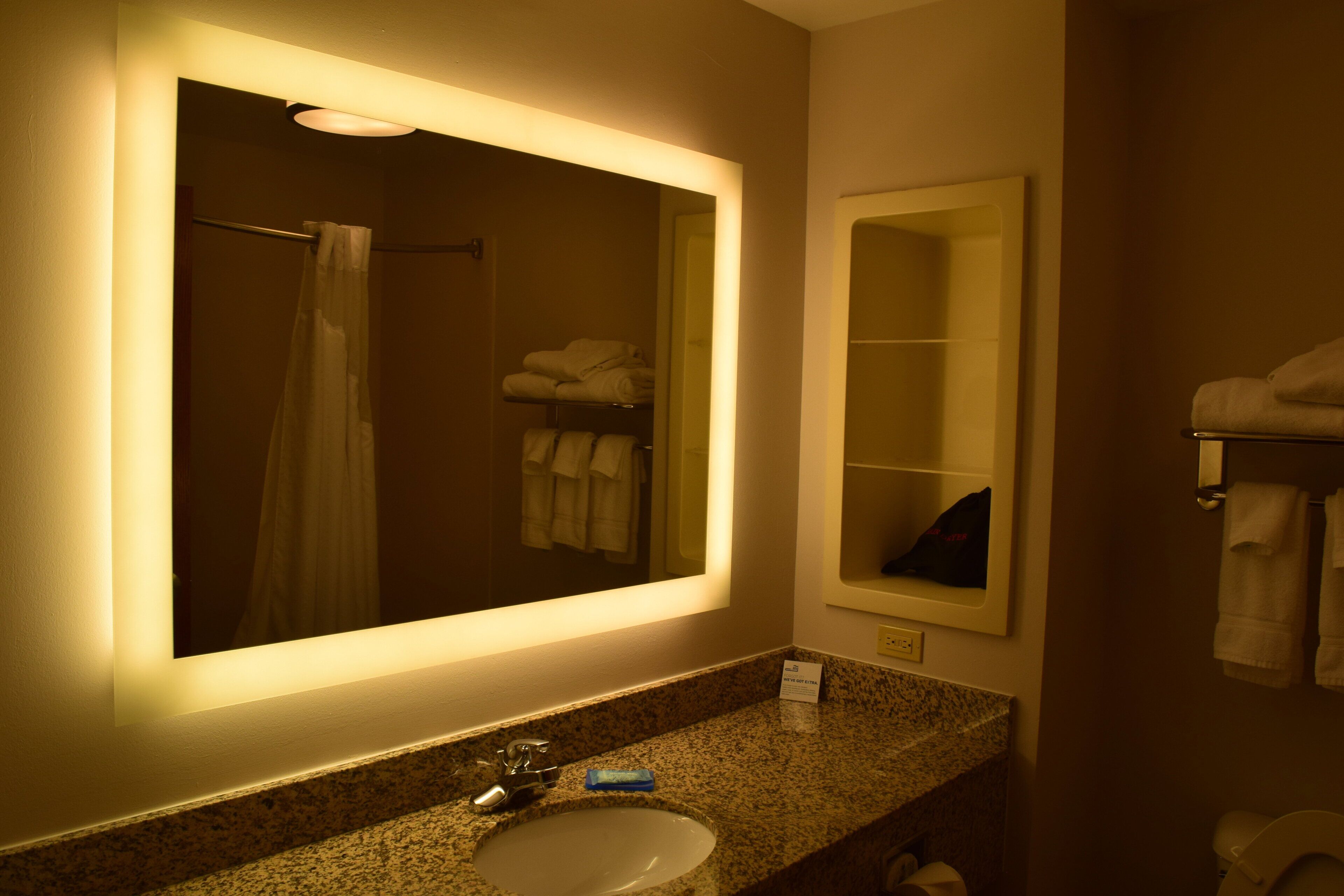 A bathroom with a large mirror, a sink, a towel rack, and a shower curtain.