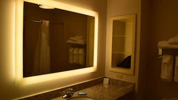 A bathroom with a large mirror, a sink, a towel rack, and a shower curtain.