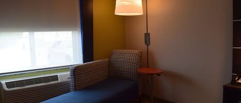 A room with a window, a radiator, a sofa, a floor lamp, and a small table.
