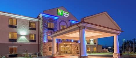 A Holiday Inn Express & Suites building with a covered entrance and a stone facade.