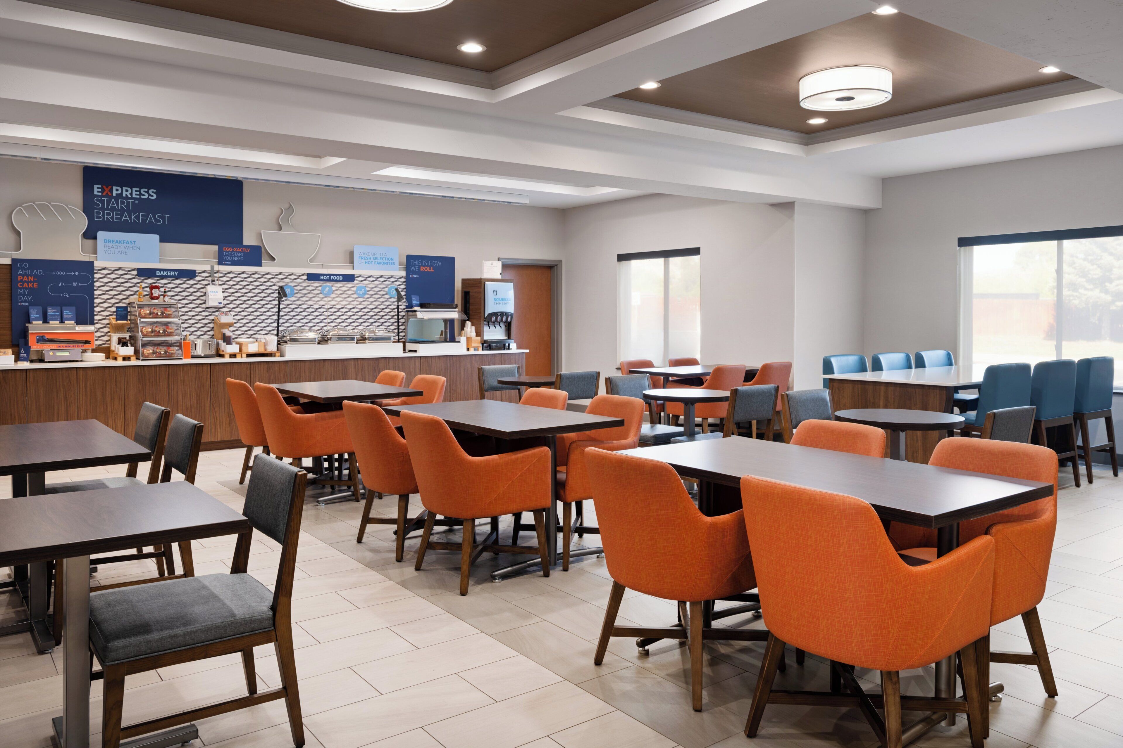 A modern breakfast area with tables and chairs, a bakery counter, and a coffee station.