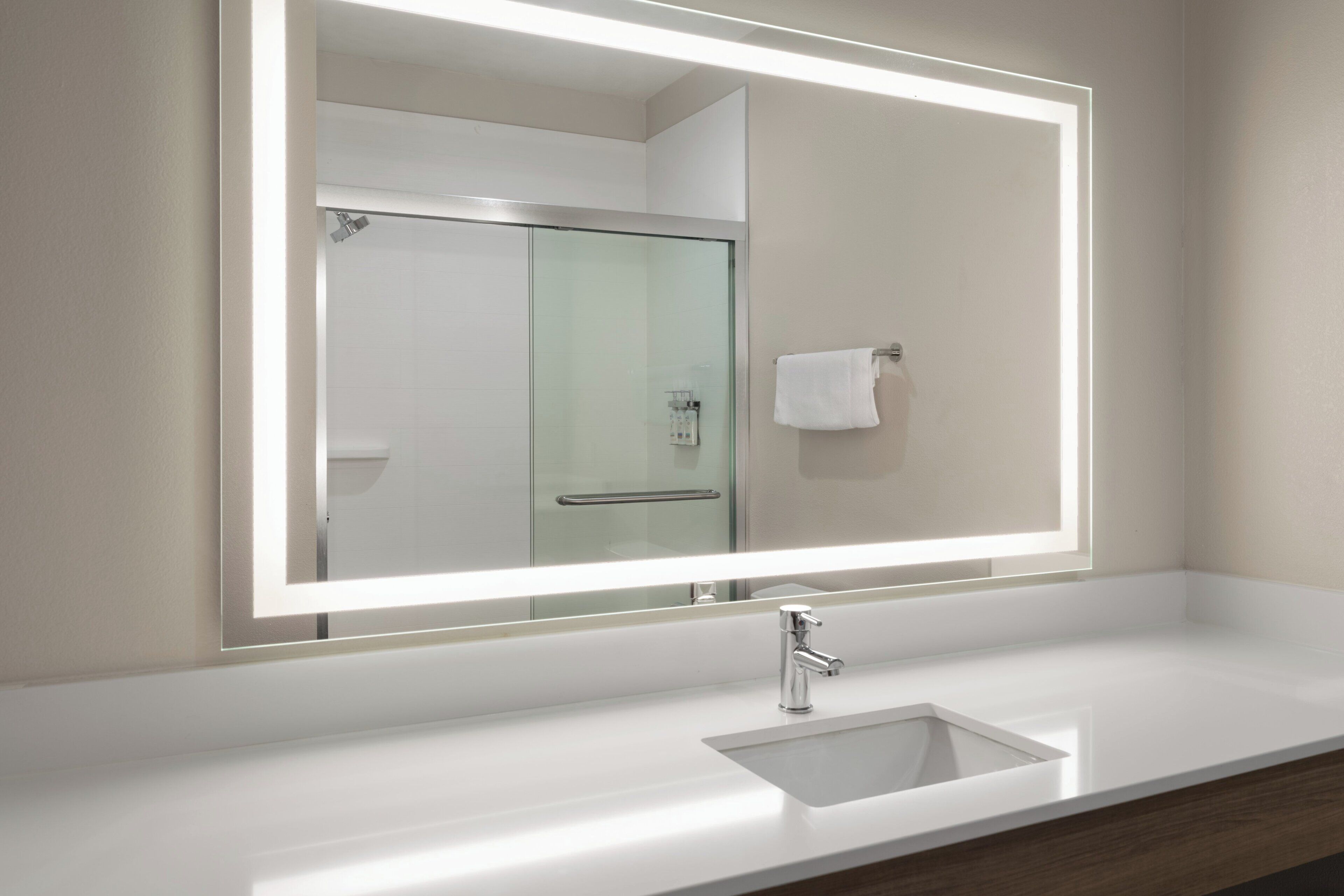 Een badkamer met een grote spiegel, een wastafel en een douchecabine met glazen wanden.