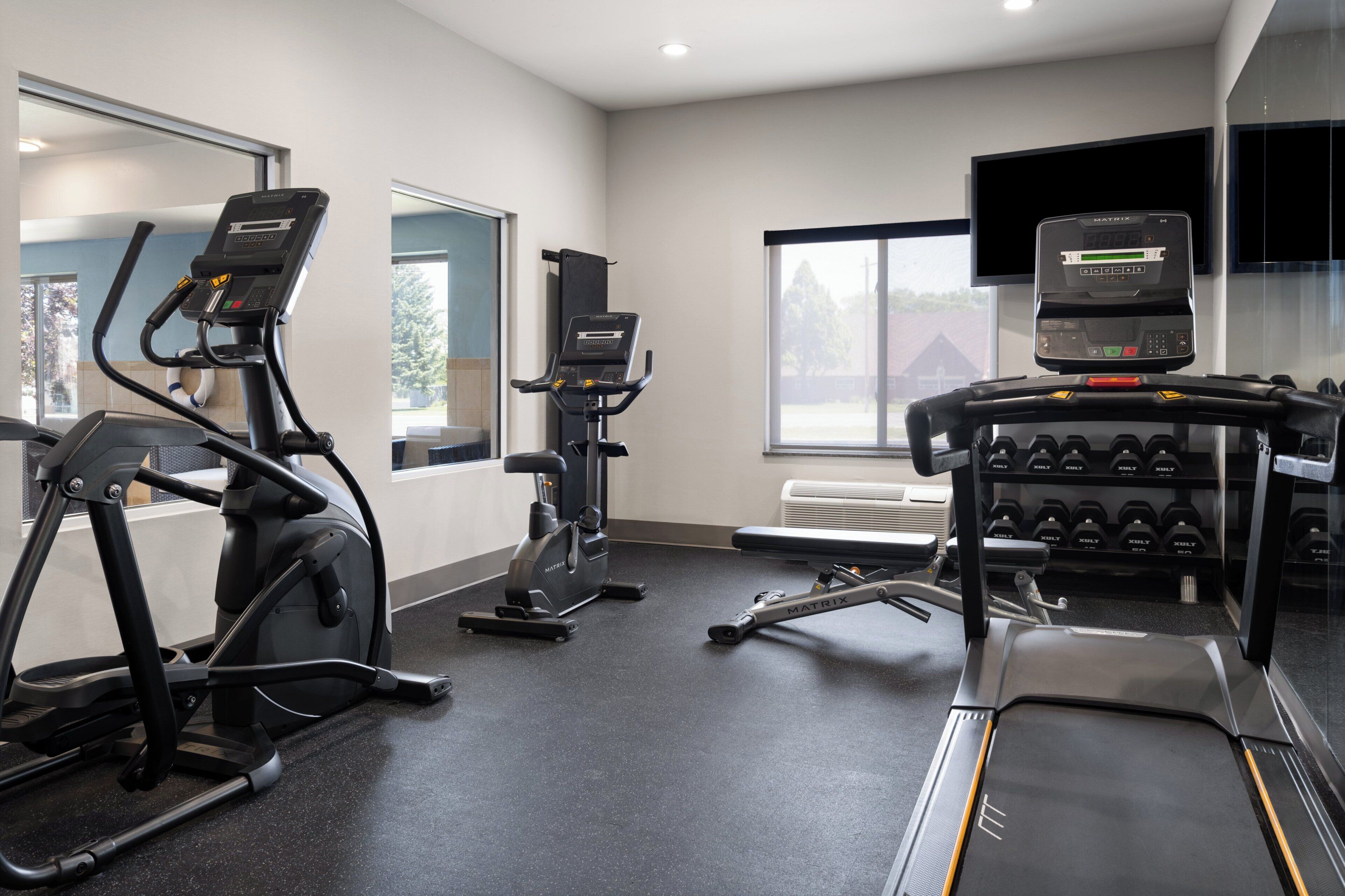A gym with treadmills, an elliptical, and a bench press area.
