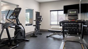 A gym with treadmills, an elliptical, and a bench press area.