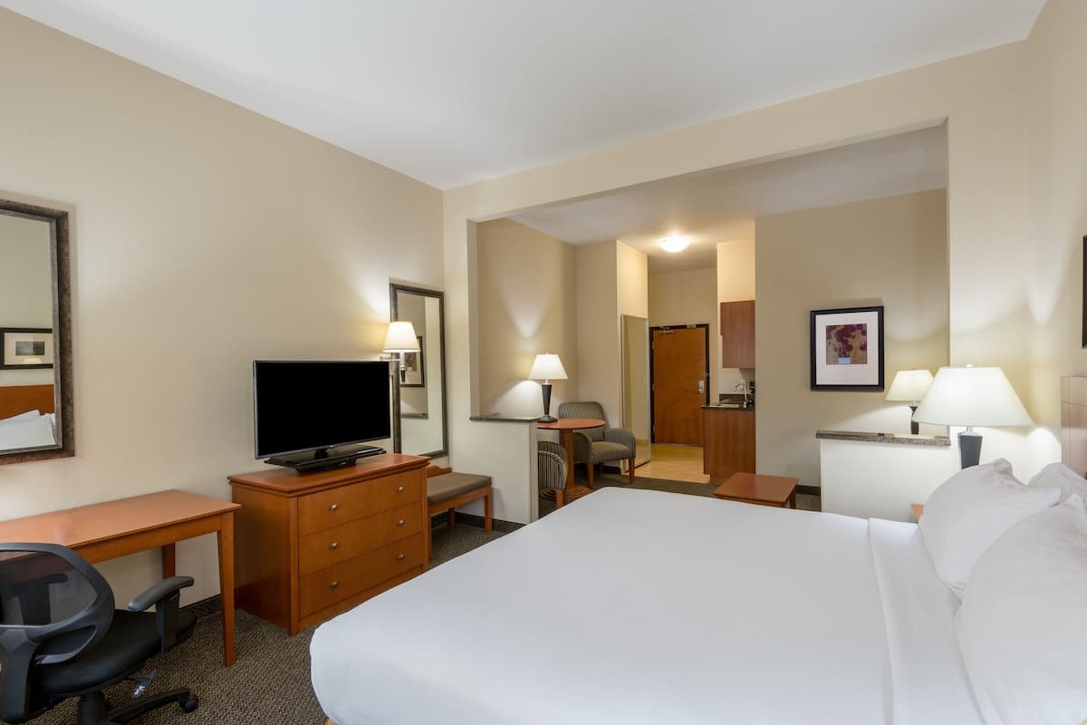 A hotel room with a bed, desk, chair, television, and a bathroom visible through an open door.