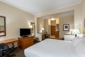 Ein Hotelzimmer mit Bett, Schreibtisch, Stuhl, Fernseher und einem durch eine offene Tür einsehbaren Badezimmer.