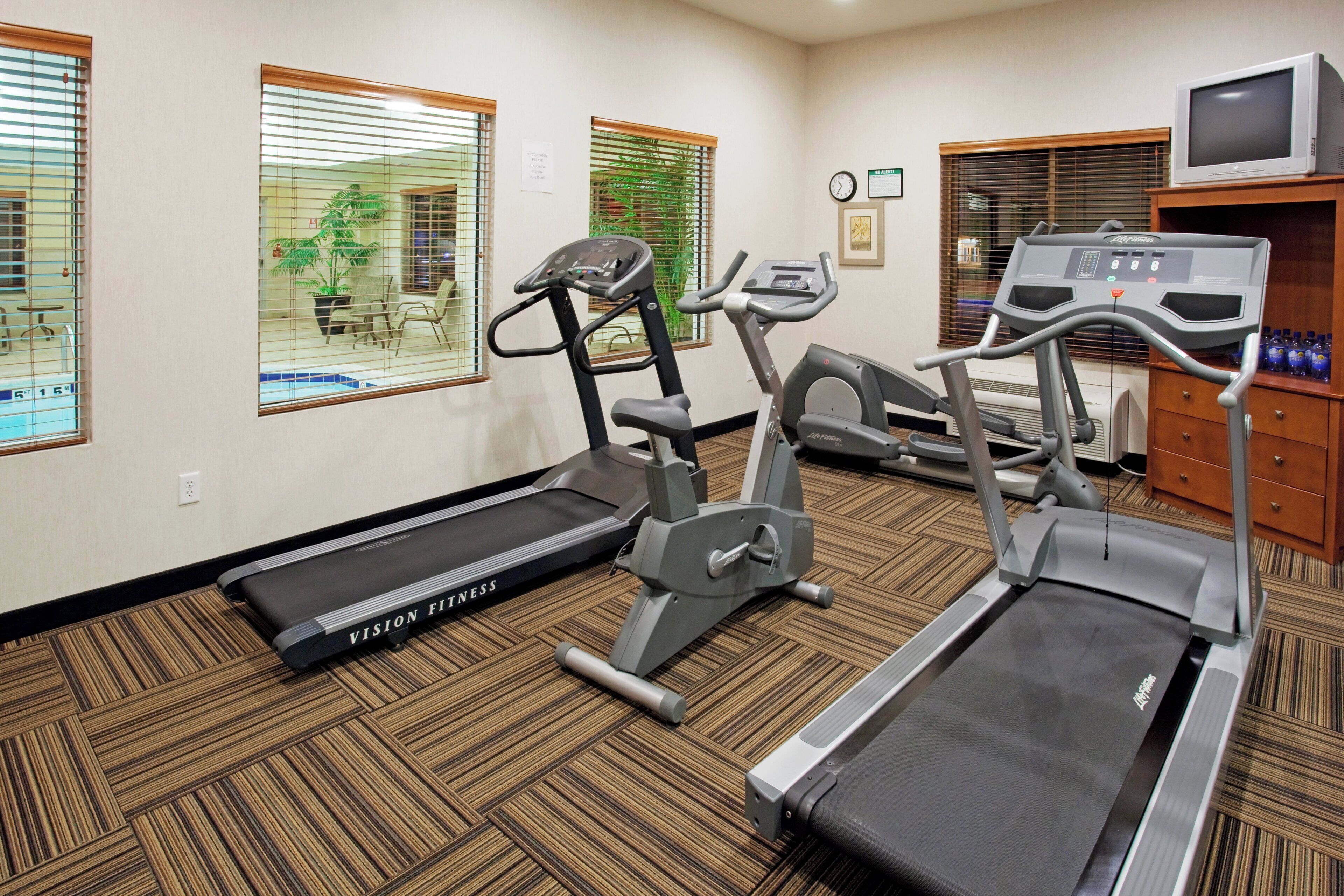 A fitness room with treadmills, a stationary bike, and a television.