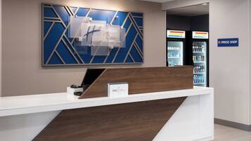 A hotel reception desk with a modern design, a sign for the Holiday Inn Express & Suites, and a visible Express Shop.