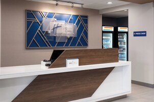 Una recepción de hotel con diseño moderno, un letrero de Holiday Inn Express & Suites y una tienda Express visible.
