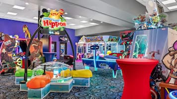 Variedad de juegos de arcade y atracciones en un espacio interior bien iluminado con alfombra estampada.