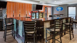 A bar area with a counter, stools, and a television screen. - Big Horn Resort, an Ascend Collection Hotel (Billings)