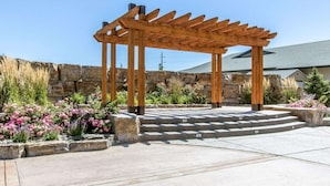 A wooden pergola structure with steps leading up to it, surrounded by a stone wall and various flowering plants. - Big Horn Resort, an Ascend Collection Hotel (Billings)