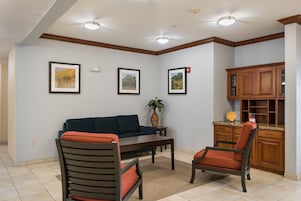 A living room with a sofa, two chairs, a coffee table, and framed pictures on the wall.