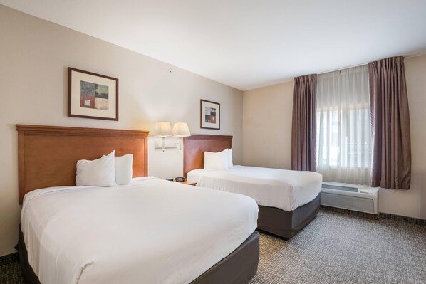 Habitación de hotel con dos camas, un ventanal con cortinas y un aire acondicionado instalado en la pared.