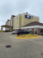 Un hotel suburbano con estacionamiento, entrada cubierta y fachada de ladrillo.