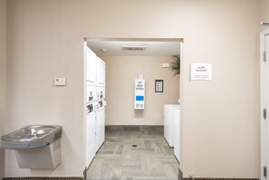 A laundry room with a sign indicating machines operate by credit card only. - Suburban Studios Waterloo (Waterloo)