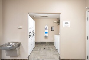 Una sala de lavandería con un letrero que indica que las máquinas funcionan únicamente con tarjeta de crédito.