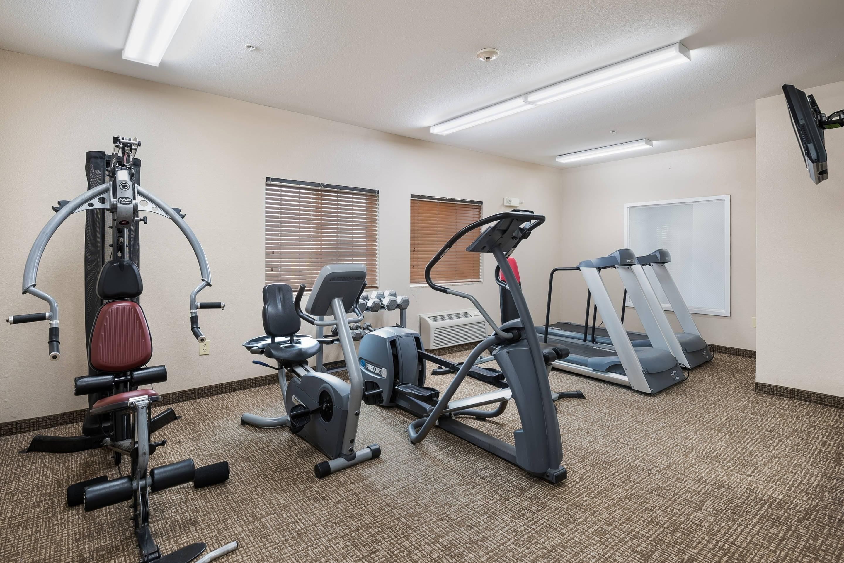A gym with various exercise equipment including a treadmill, elliptical, and weight machines.