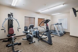 A gym with various exercise equipment including a treadmill, elliptical, and weight machines.