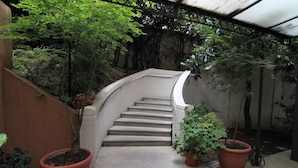 A concrete staircase leading up to a covered area with potted plants and trees. - Hotel Metro (Milan)