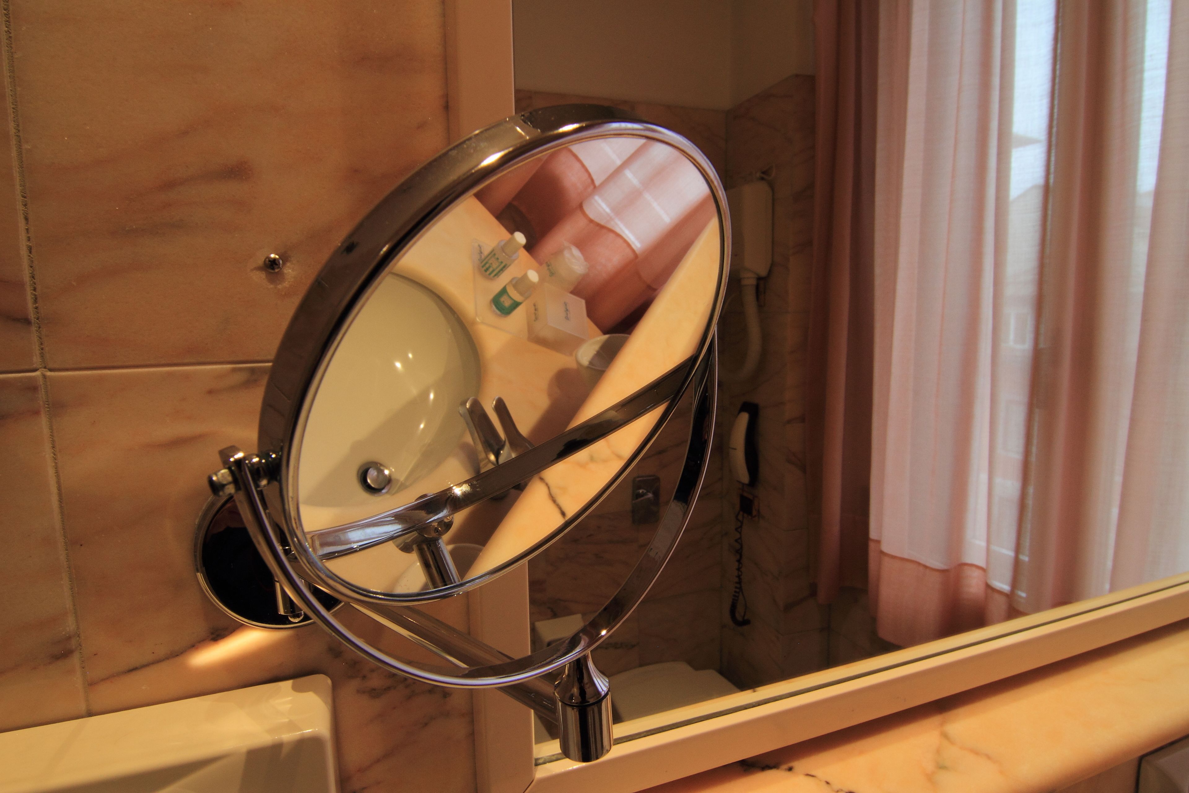 A bathroom with a round mirror, a sink, and a shower area.