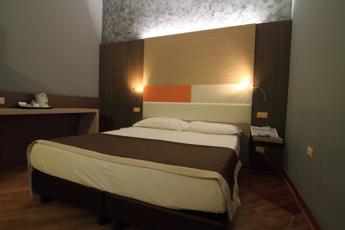 A neatly made bed with a brown headboard and two bedside lamps.