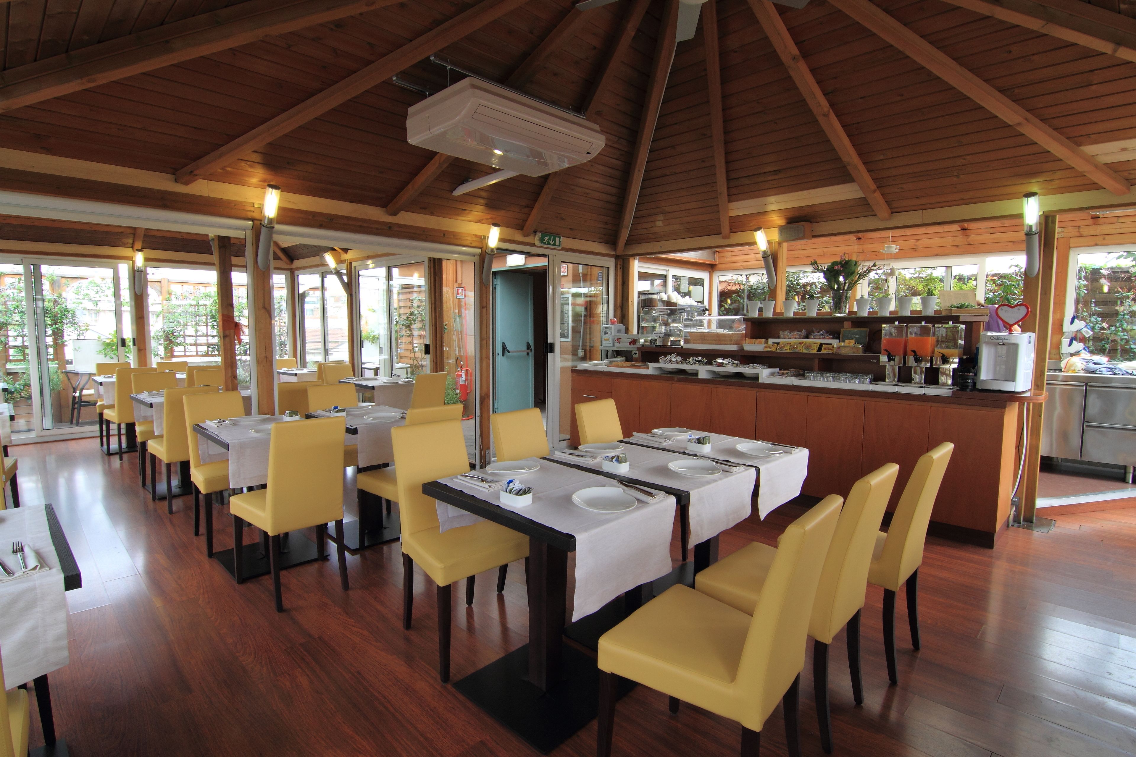 A restaurant with wooden beams, yellow chairs, and tables set for dining.