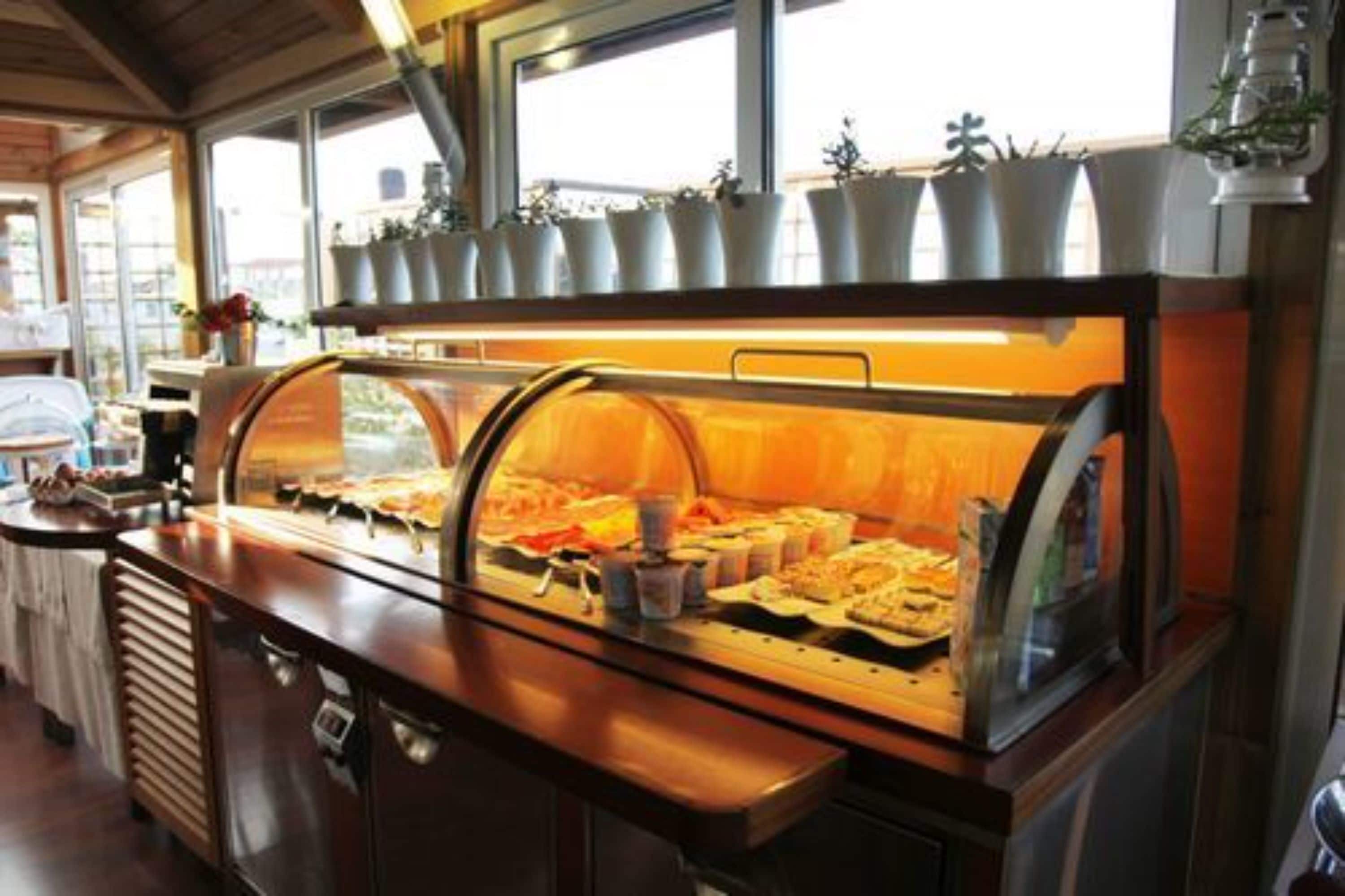 A buffet setup with various food items and a glass enclosure, likely in a restaurant or hotel setting.