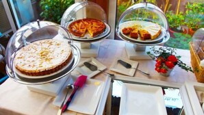 A buffet setup with various dishes under glass domes, a knife, and a small vase with red flowers. - Hotel Metro (Milan)