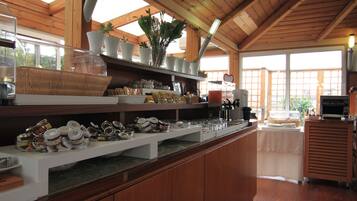 A kitchen with wooden cabinets, a countertop with various food items, and a window with a view of greenery.