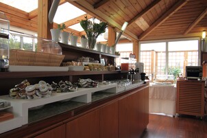 Een keuken met houten kastjes, een aanrecht met verschillende etenswaren en een raam met uitzicht op groen.