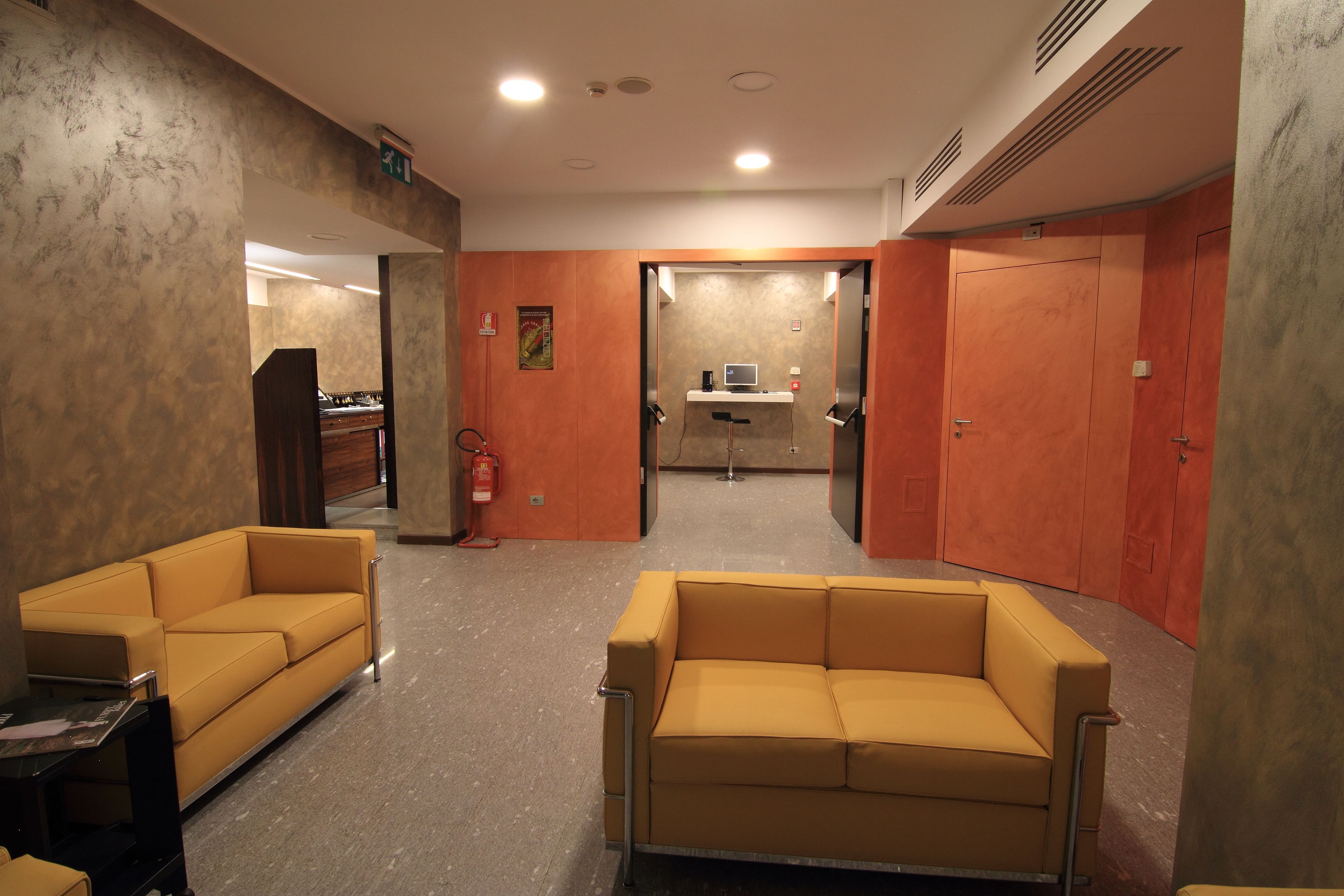 A lobby with two yellow sofas, a reception desk, and a small kitchenette area.
