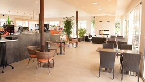 A spacious indoor area with multiple seating arrangements, including wicker chairs and tables, and a bar area with a counter and various items. - Apartamentos Sol Romántica by DOT Suites (Manacor)