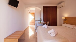A hotel room with a bed, a desk, a chair, a TV mounted on the wall, and an air conditioning unit. - Apartamentos Sol Romántica by DOT Suites (Manacor)
