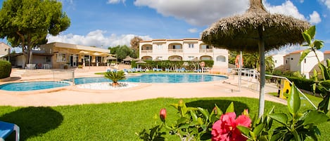 Una piscina al aire libre, sombrillas, sillones reclinables de piscina