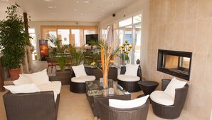 A modern lobby with wicker furniture, a glass coffee table, and a flat-screen TV mounted on the wall. - Apartamentos Sol Romántica by DOT Suites (Manacor)