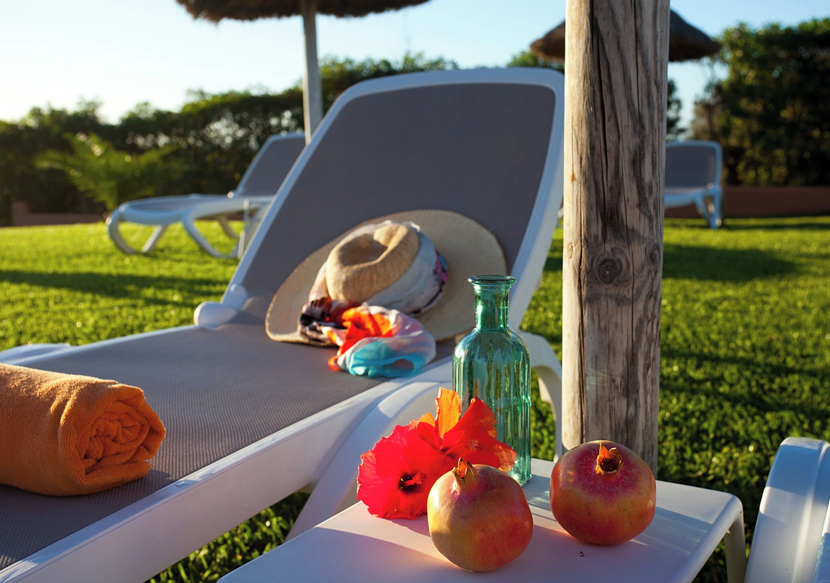 Una silla de salón con un sombrero, una botella y frutas sobre una mesa.