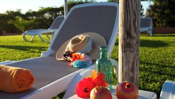 Una silla de salón con un sombrero, una botella y frutas sobre una mesa.