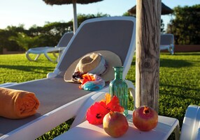 Una silla de salón con un sombrero, una botella y frutas sobre una mesa.