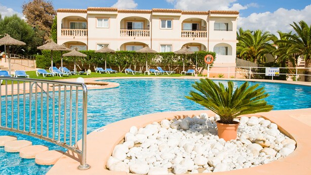 A hotel with a swimming pool, lounge chairs, and a palm tree. - Apartamentos Sol Romántica by DOT Suites (Manacor)