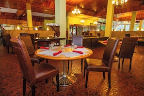 Enjoy dining in a warm and inviting atmosphere with round tables, comfortable seating, and a stylish tile floor.